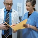 oral surgeon reviewing medical records and a dental procedure cross-reference for medical cross coding for oral surgery procedures